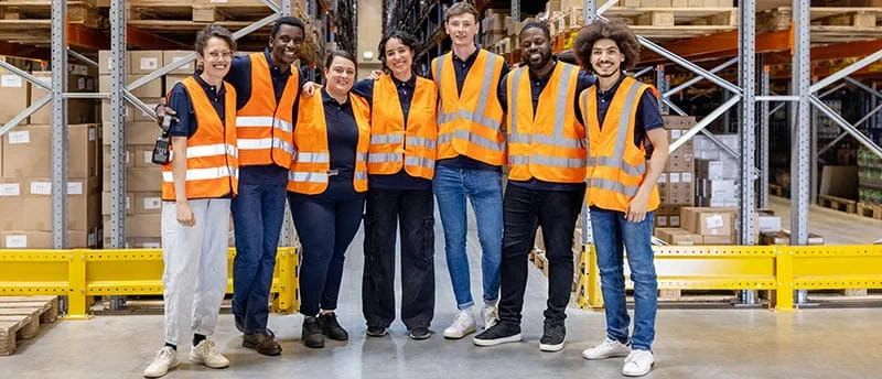 Gruppe von Arbeitern in einer Lagerhalle mit Warnwesten - DIS AG
