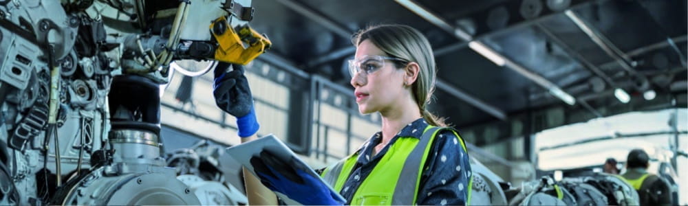 Arbeiterin mit Schutzbrille macht Unterscuhungen an einer Maschine Arbeiterin mit Schutzbrille macht Unterscuhungen an einer Maschine